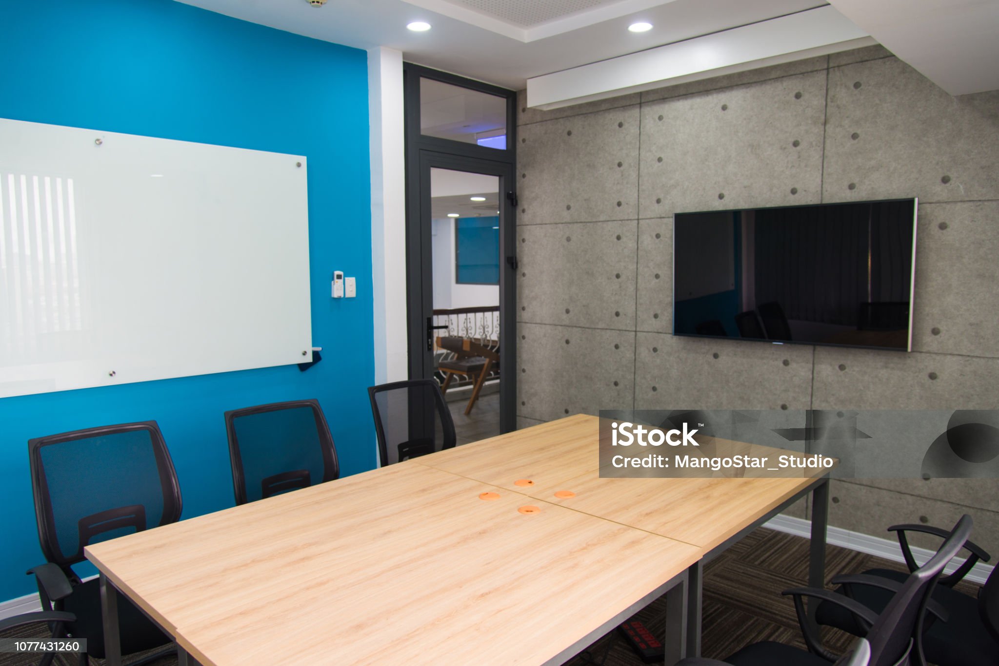 Conference room with television set and whiteboard on walls. Wooden table and chairs in center of urban design meeting room. Office concept